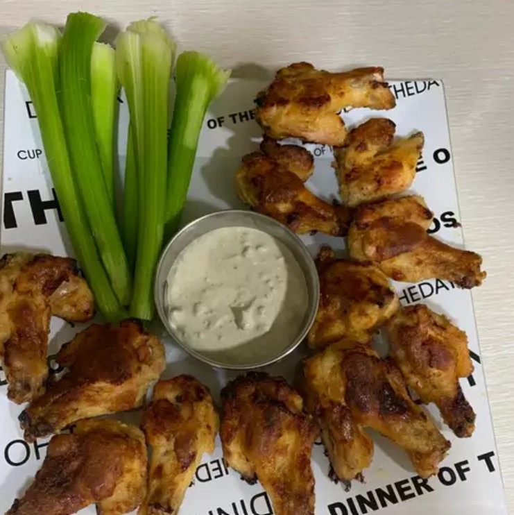 Plate of crispy Baked Boneless Buffalo Wings with fresh garnish and dipping sauces