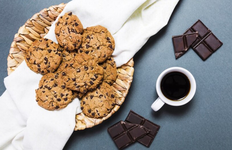 Freshly baked chocolate chip cookie bars on a rustic wooden table, sprinkled with sugar.