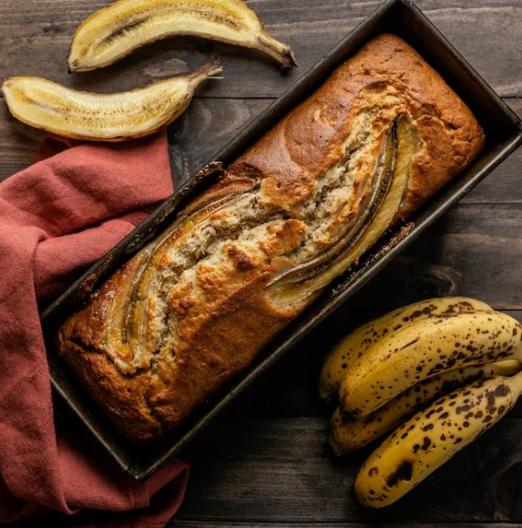 Freshly baked Banana Walnut Cake on a serving plate with walnuts scattered around"